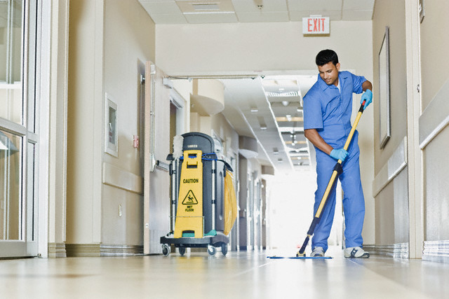 Janitor in hospital hallway --- Image by © Simon Jarratt/Corbis