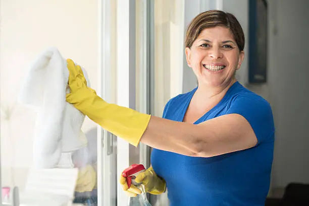 Mature hispanic woman housekeeping cleaning a window